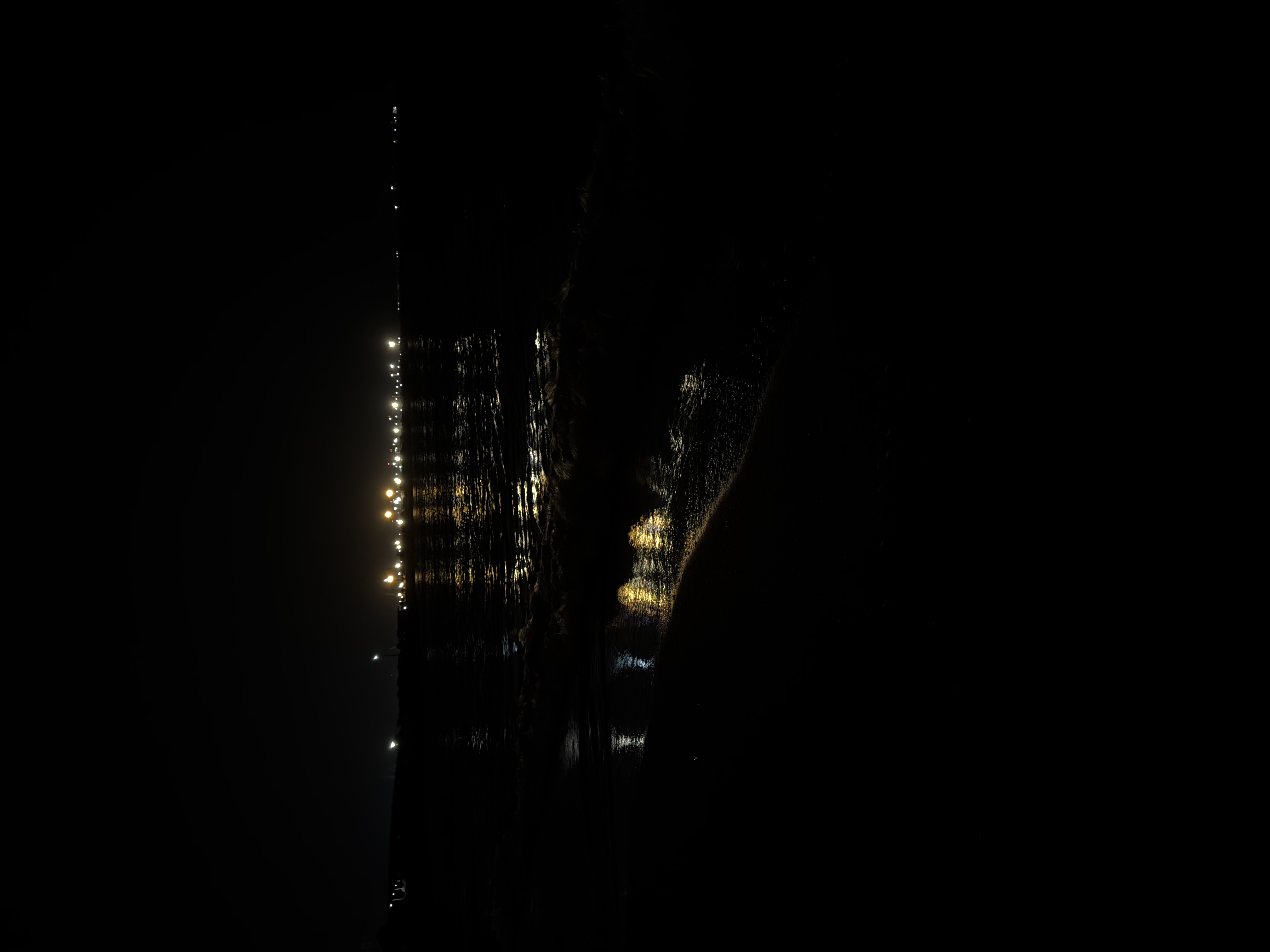 Distant lights across dark water at night
