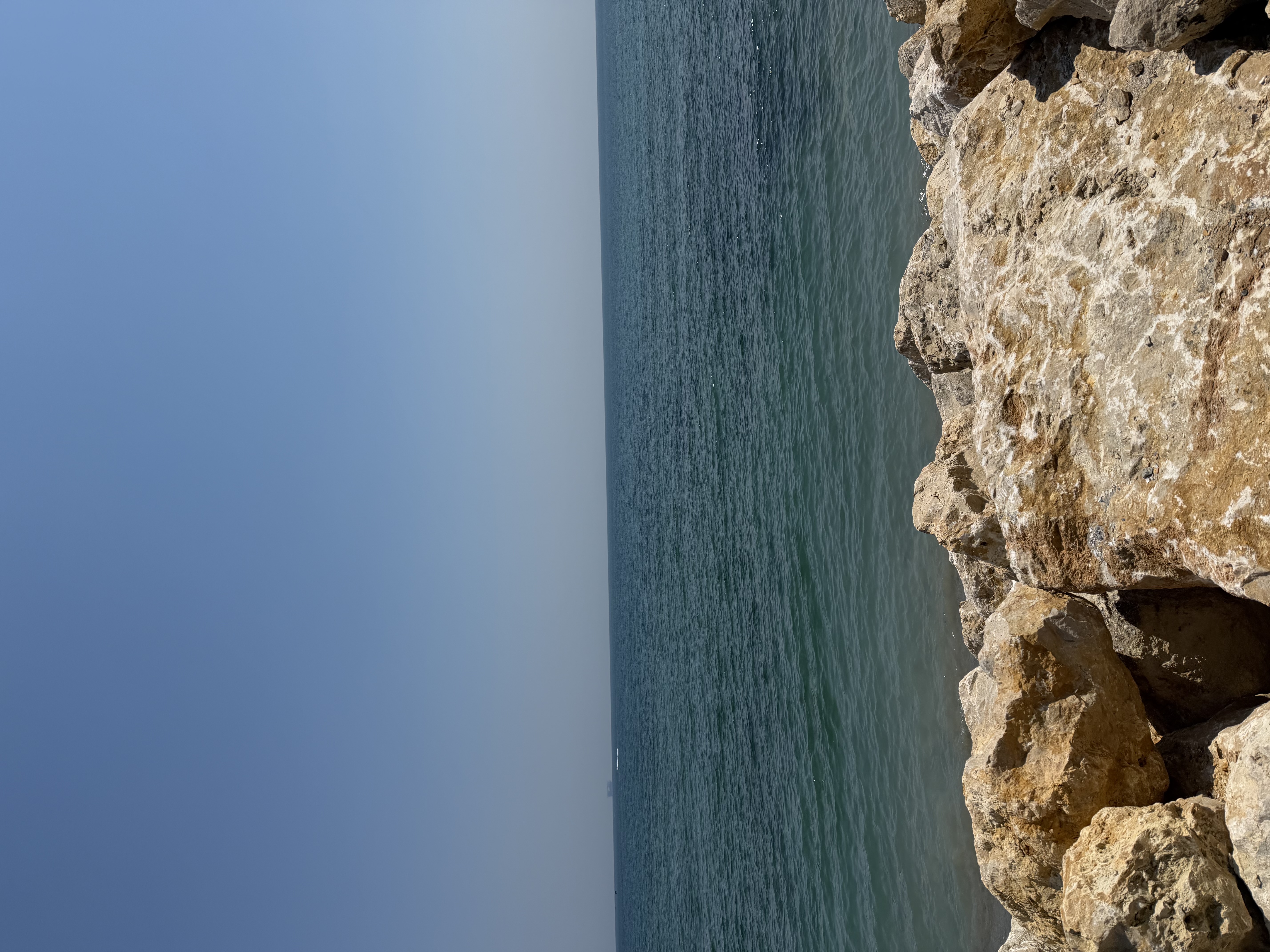 Rocks along a shoreline under a clear blue sky