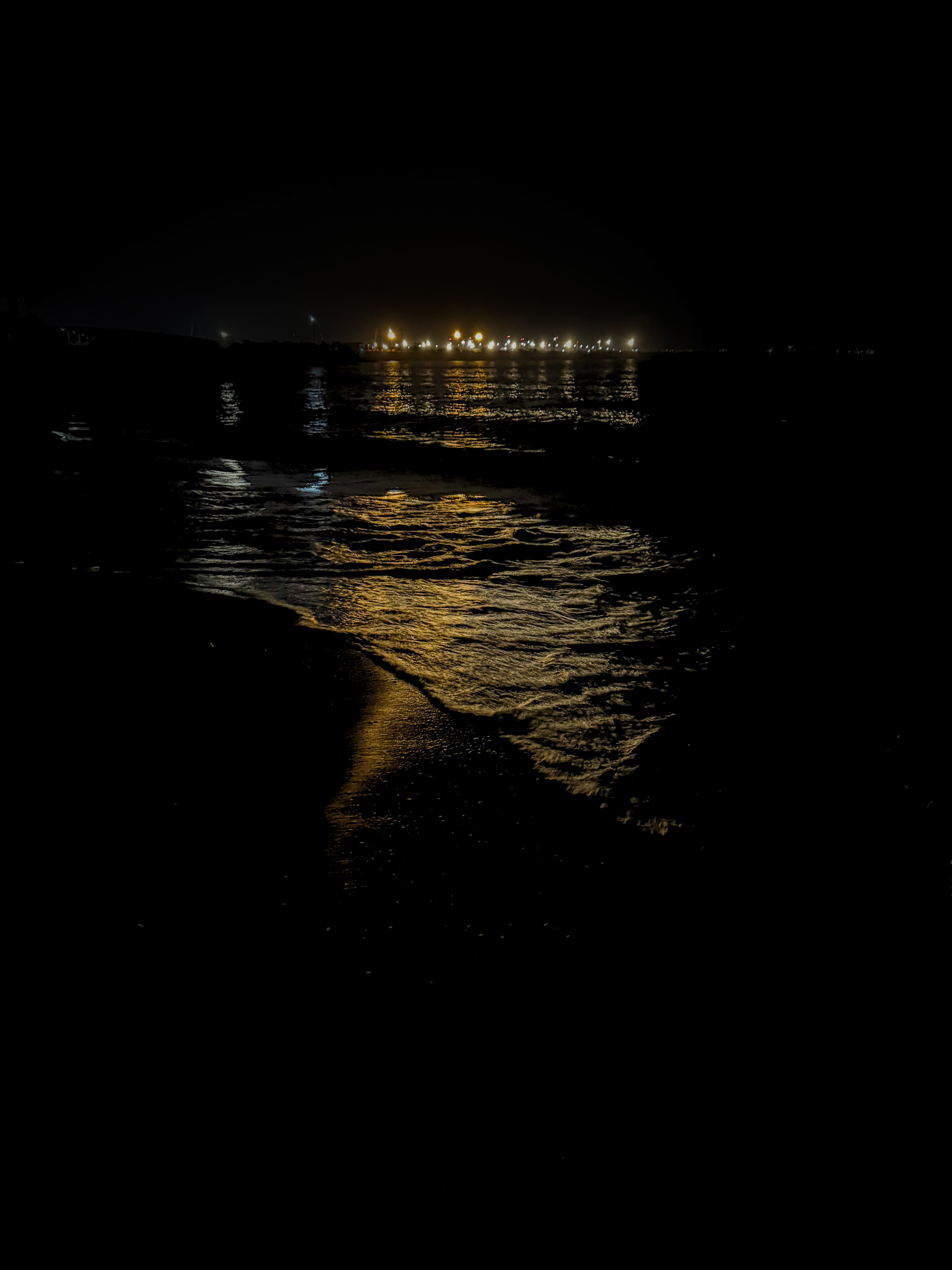 Dark shoreline with golden light on the water